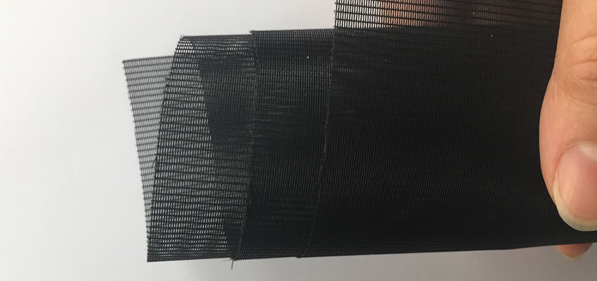 A small coil of black anti-smog window screen held by a hand.