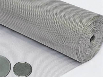 There is a roll of hastelloy C-276 wire mesh with two filter discs next to it.