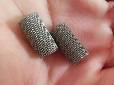 Two small hastelloy C-276 mesh filter tubes are in one hand.
