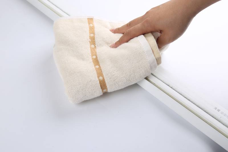 A hand is cleaning the window frame with towel.