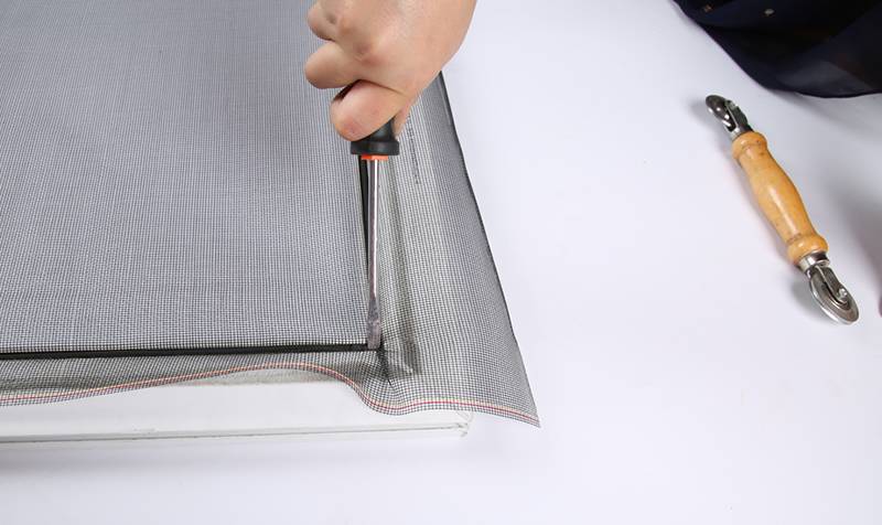 A worker is push splines into corner down with a screwdriver.