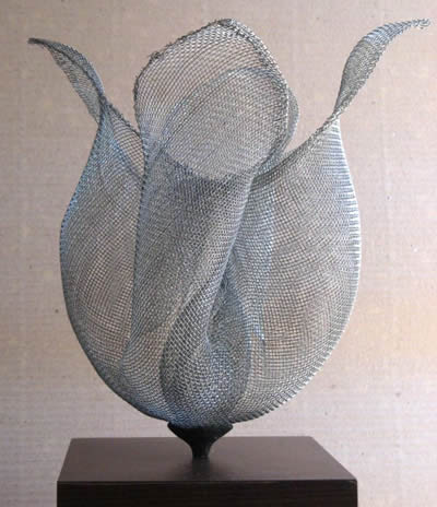 There is a silver wire cloth artwork stand on a table.