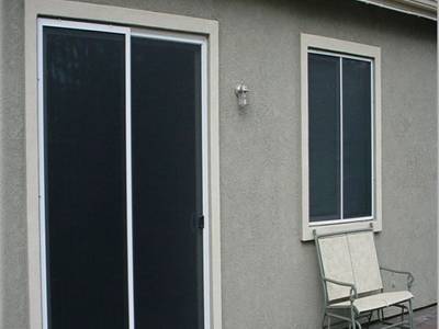 A double-leaf door and a window is covered with solar screen.