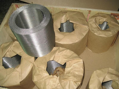 Several reverse dutch mesh belt rolls wrapped with waterproof paper stand in a wooden case.