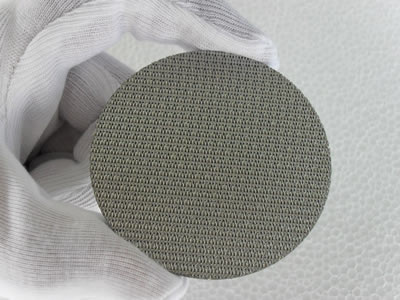 There is a dutch weave stainless steel filter disc in one hand.